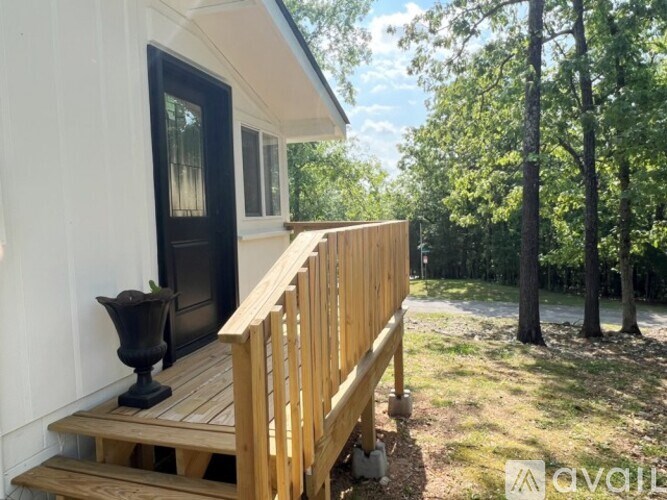 A wooden deck with a black vase and a window.