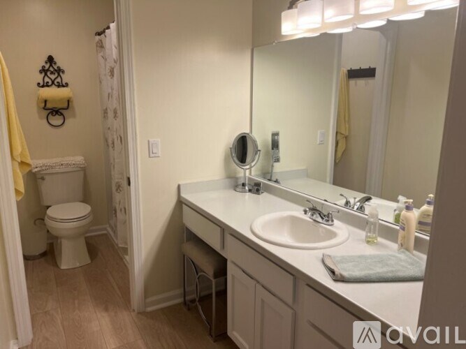 A bathroom with a toilet, sink, mirror, and a towel.