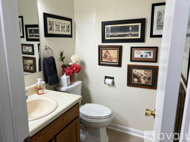 A bathroom with a toilet, sink, and pictures on the wall.