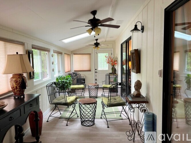 A sunroom with a ceiling fan and patio furniture.