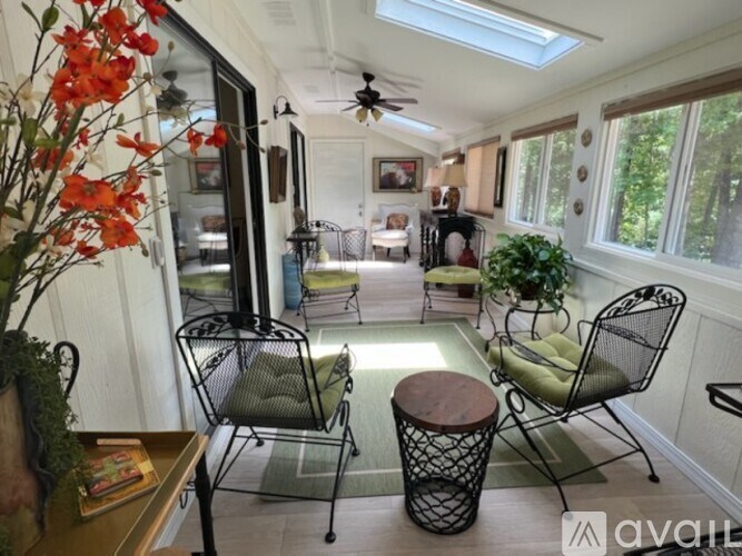 A sunroom with a ceiling fan and two chairs.