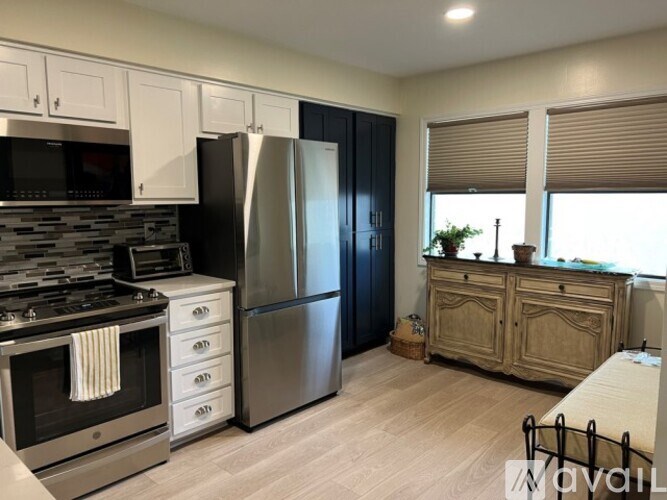 A kitchen with a stove, refrigerator, and cabinets.