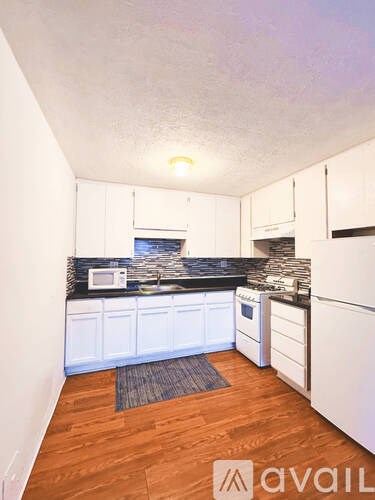 A kitchen with white cabinets and a black countertop.