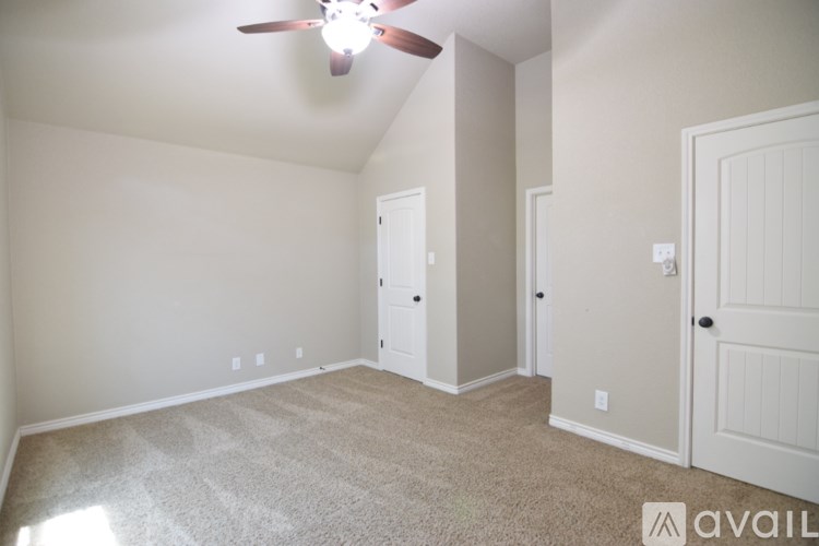 A bedroom with a bed, a ceiling fan, and a television.