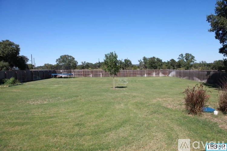 A grassy field with a fence and a small tree in the distance.