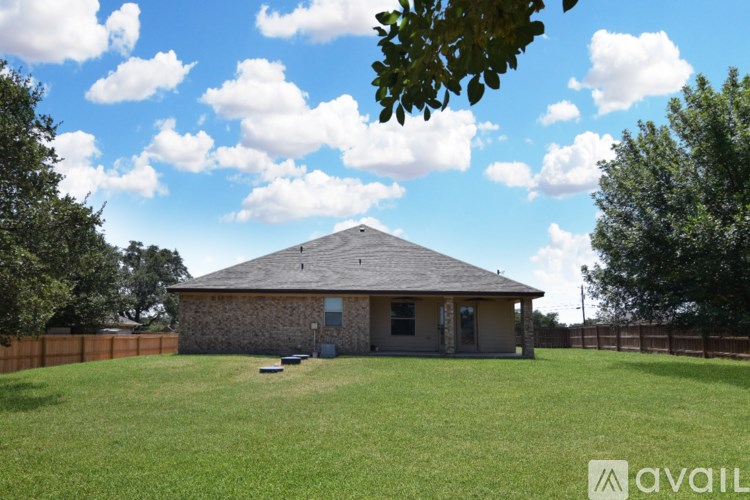 A grassy field with a house and fence in the background.