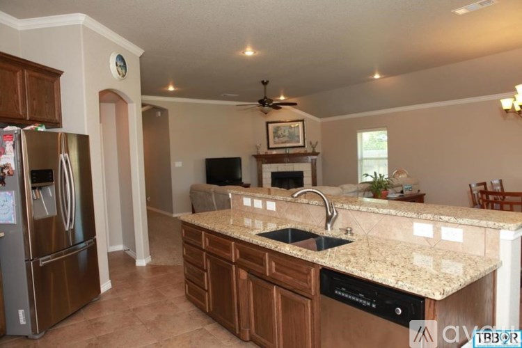 A kitchen with brown cabinets and granite countertops.