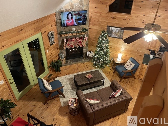 A living room with a television, a couch, a chair, a coffee table, and a Christmas tree.