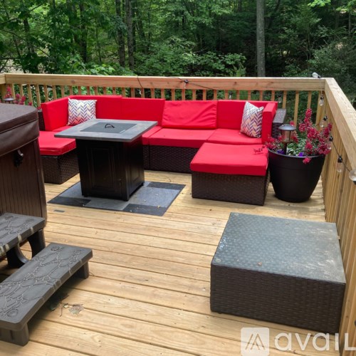 A wooden deck with a red couch and a black coffee table.