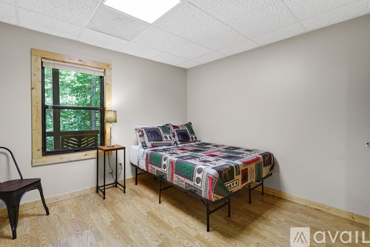 A bedroom with a bed, chair, and window.