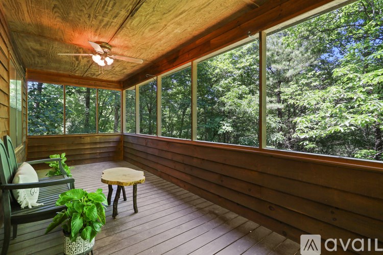 A wooden balcony with a table and chairs and a potted plant.