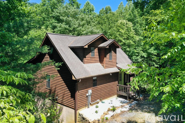 A house with a brown roof is surrounded by green trees.