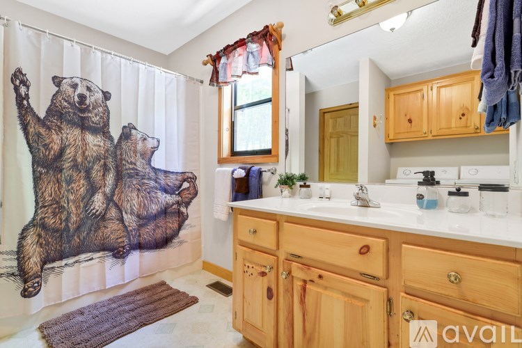 A bathroom with wooden cabinets and a bear shower curtain.