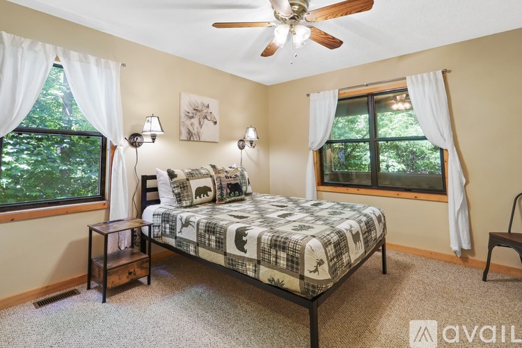 A bedroom with a bed, nightstand, and window.