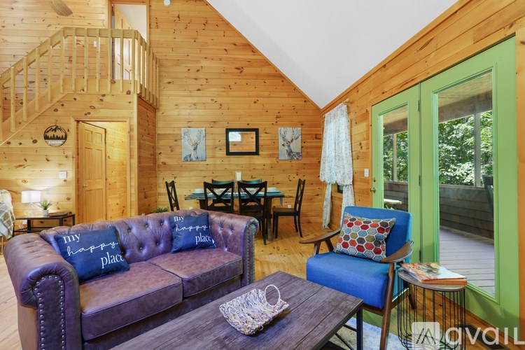 A living room with a purple couch and a wooden staircase.