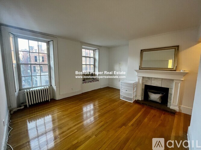 A large empty room with wood floors and a fireplace.