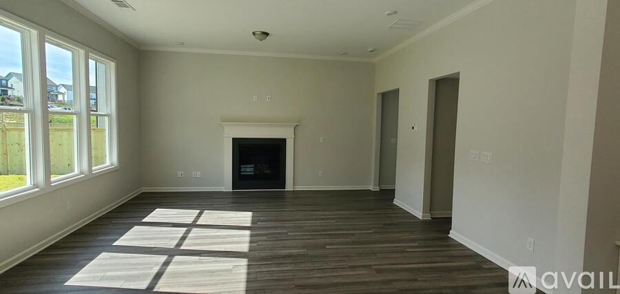 A large empty room with wooden floors and a fireplace.