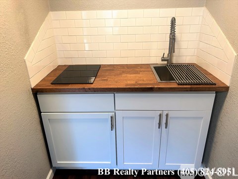 A kitchen with a white wall and a wooden counter top.