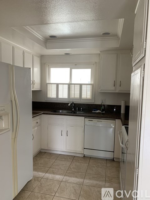A kitchen with white cabinets and a white refrigerator.