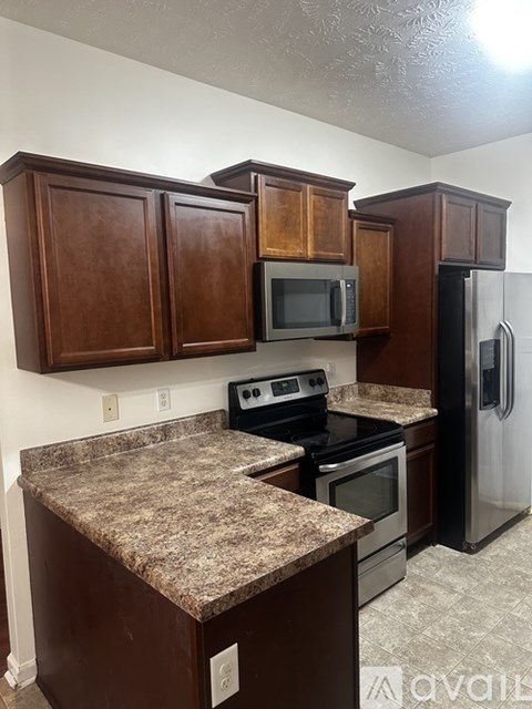 A kitchen with brown cabinets and granite countertops.