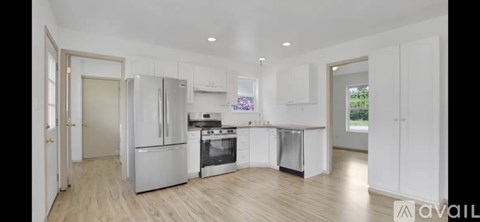A modern kitchen with white cabinets and stainless steel appliances.