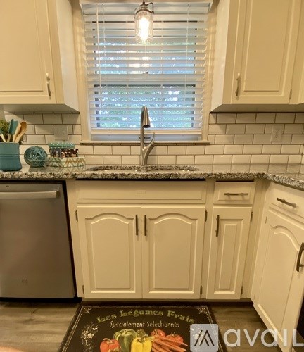 A kitchen with white cabinets and a black counter top.