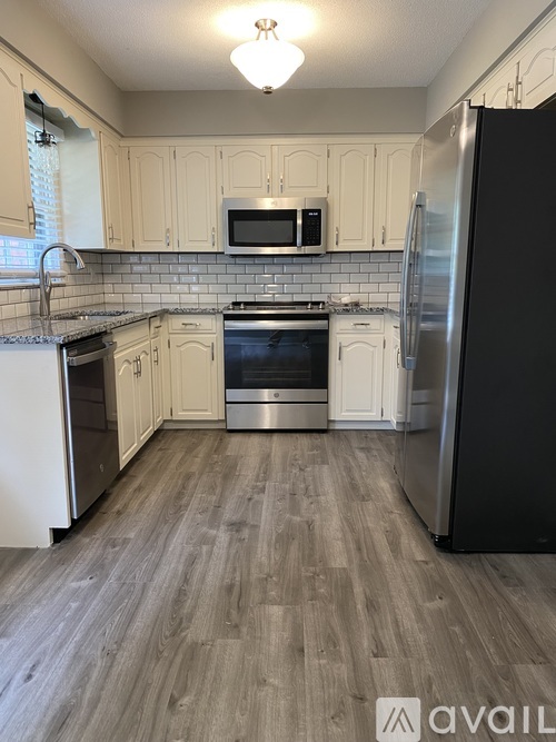 A kitchen with a black refrigerator and white cabinets.