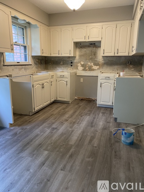 A kitchen with wooden floors and cabinets under renovation.