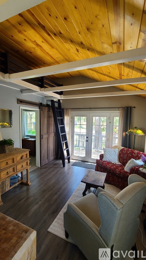 A living room with a wooden ceiling and a red couch.