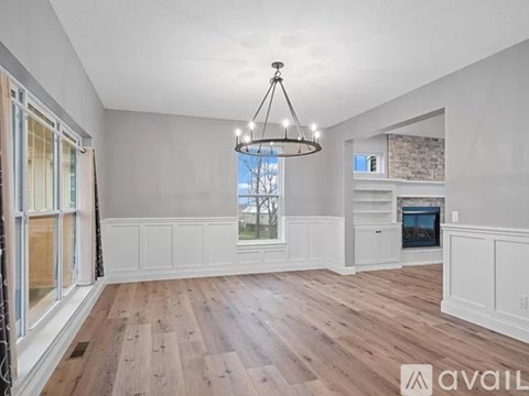 A spacious living room with wooden floors and a chandelier.