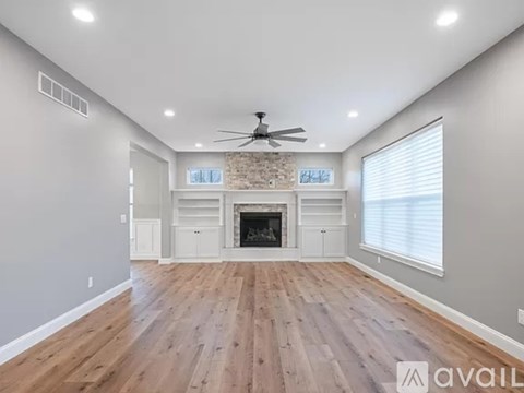 A spacious room with a fireplace and wooden flooring.