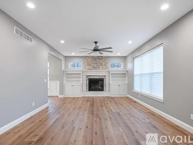 A spacious room with a fireplace and wooden flooring.