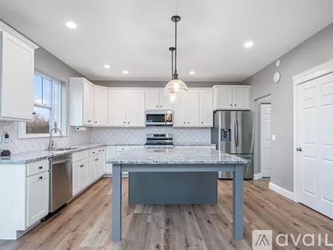 A kitchen with a table in the middle and a fridge to the side.