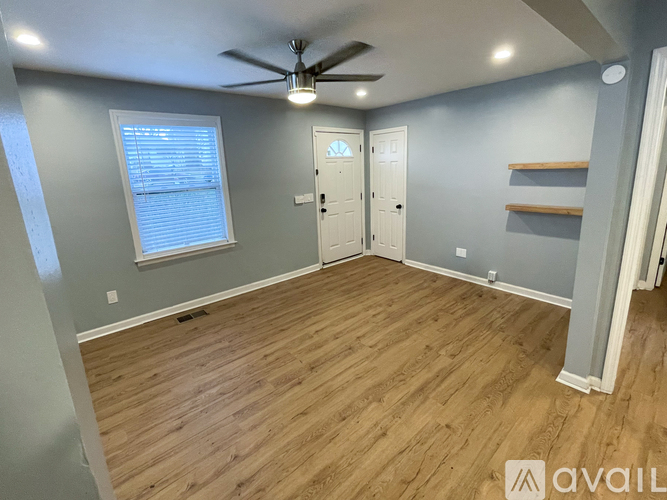 A room with a ceiling fan and wooden flooring.