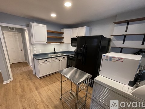 A kitchen with white appliances and wooden floors.