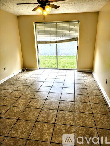 A room with a ceiling fan and a sliding glass door leading to a grassy area.