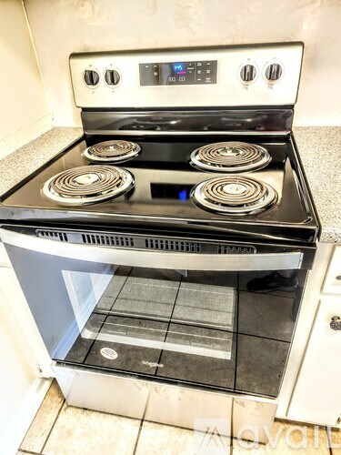 A stove top oven with four burners and a digital control panel.