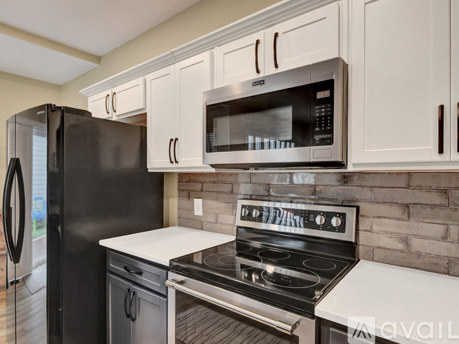 A black refrigerator and microwave are on a kitchen counter.