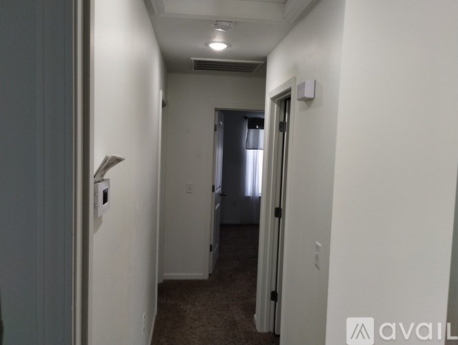 A hallway with a carpeted floor and white walls.