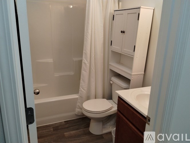A white toilet in a small bathroom with a white shower curtain.