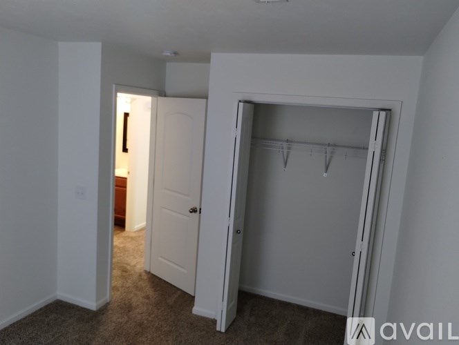 A room with a white door and a white closet with hangers.