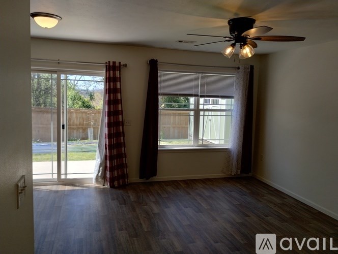 A room with a ceiling fan and sliding glass doors.