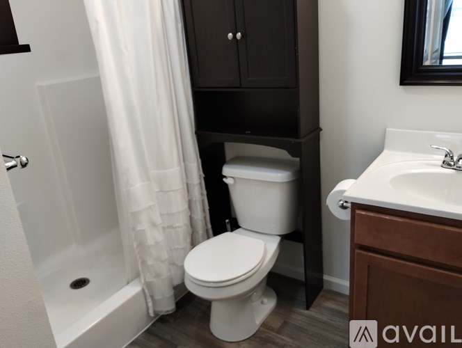 A white toilet in a bathroom with a white shower curtain.