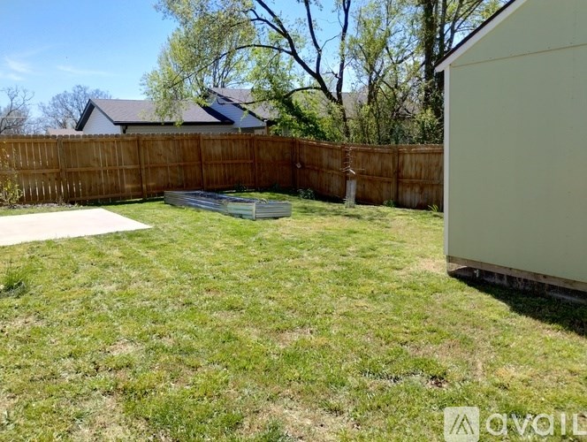 A backyard with a wooden fence and a white shed.