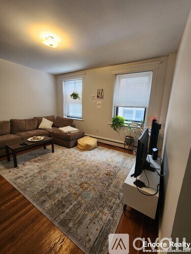 A living room with a brown couch and a rug.