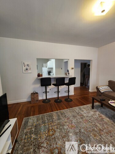 A living room with a grey rug and a black chair.