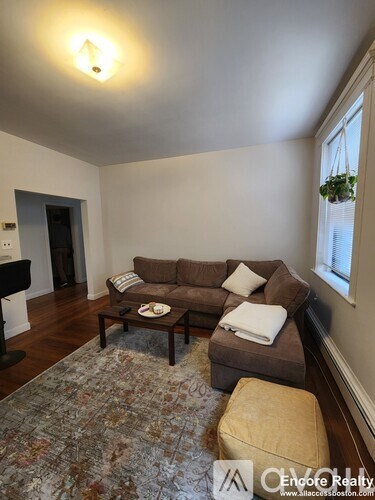 A living room with a brown couch and a rug.