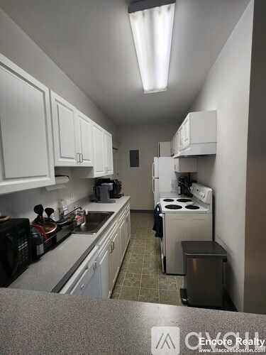 A kitchen with white cabinets and a black microwave.
