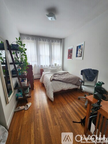 A bedroom with a bed, a desk, and a chair.