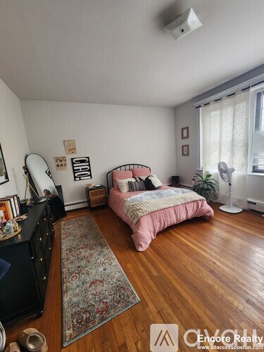 A bedroom with a pink bed and a rug on the floor.
